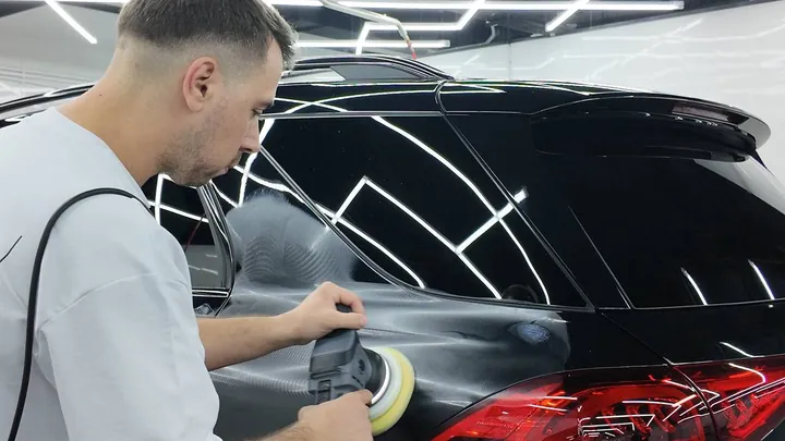 Мастер полирует кузов чёрного Mercedes роторной машинкой